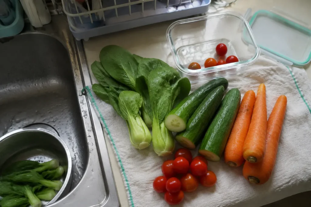 Washed leafy vegetables cucumber carrots and tomatoes ready for later meals